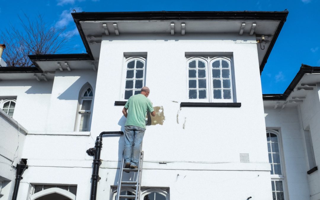 Un artisan peint une maison