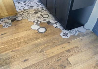 Photo du parquet du salon qui s'incruste avec les carreaux hexagonaux du carrelage de la cuisine