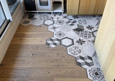 Photo du parquet du salon qui s'incruste avec les carreaux hexagonaux du carrelage de la cuisine